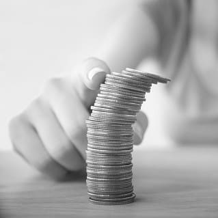 Hand spielt mit Münzturm als Synonym für monetären Erfolg und Umsatzsteigerung